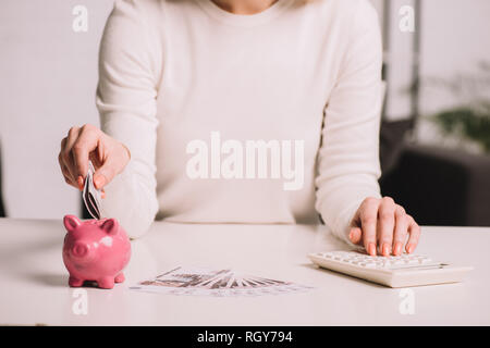 Den mittleren Abschnitt der Frau mit Taschenrechner und der russische Rubel in piggy Bank Stockfoto