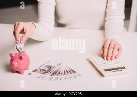 7/8 Schuß von Frau mit Taschenrechner und der russische Rubel in piggy Bank Stockfoto