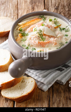 Köstliche cremige Fischsuppe mit Kabeljau und Lachs close-up in eine Schüssel mit frischem Brot auf dem Tisch serviert. Vertikale Stockfoto