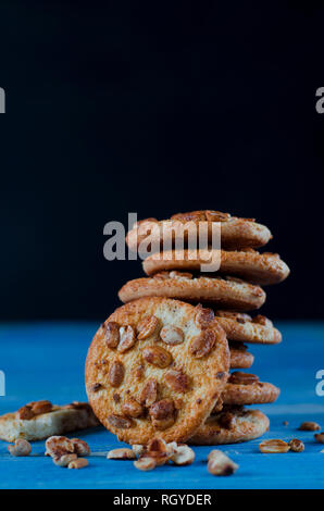 Runde orange Biscuits mit bunten kandierte Früchte und ein Stück saftige Orange liegen auf einem Holztisch. Nahaufnahme Stockfoto