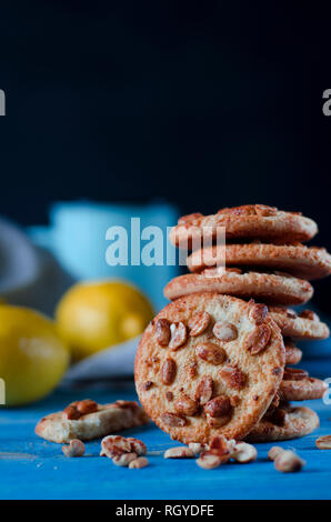 Runde orange Biscuits mit bunten kandierte Früchte und ein Stück saftige Orange liegen auf einem Holztisch. Nahaufnahme Stockfoto