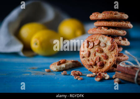 Runde orange Biscuits mit bunten kandierte Früchte und ein Stück saftige Orange liegen auf einem Holztisch. Nahaufnahme Stockfoto