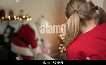 Ein junges Mädchen um die Ecke spähen entdeckt Santa in Ihrem Wohnzimmer am Heiligabend. Stockfoto