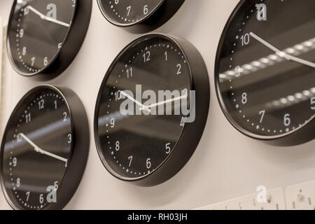 Viele verschiedene Wanduhr auf der Wand. Satz von clockfaces isoliert. Konzept der zeit management. Mehrere Uhren mit verschiedenen Zeit. Schwarz Wanduhren Stockfoto