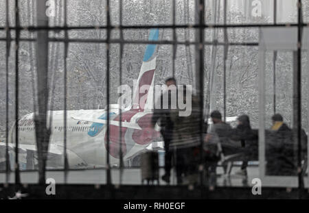 31. Januar 2019, Nordrhein-Westfalen, Köln: Reisende warten vor schneebedeckten Flugzeuge am Flughafen Köln/Bonn in der Klemme. Der Flughafen wurde nach Schneefällen geschlossen. Foto: Oliver Berg/dpa Stockfoto