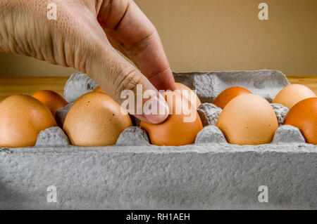 Nahaufnahme der männlichen Hand, denn ein Hühnerei aus der Pappe ei Box. Stockfoto