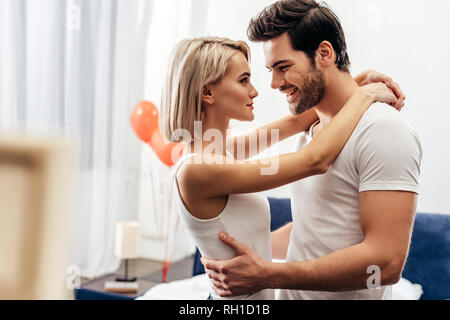 Selektiver Fokus der attraktive Freundin und gutaussehenden Freund umarmen im Schlafzimmer am Valentinstag Stockfoto