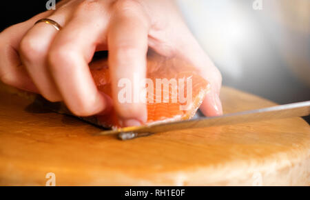 Koch schneidet red fish weibliche Hand mit Messer Stockfoto