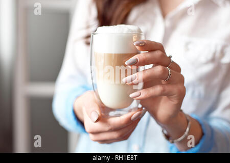 In der Nähe der weiblichen Händen im Büro Kleidung hält ein Glas Tasse Kaffee mit Sojamilch während einer Pause bei der Arbeit, Lifestyle Konzept Stockfoto