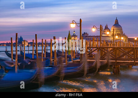 Basilica di Santa Maria della Salute und Gondeln auf dem Meer bei Sonnenaufgang/Sonnenuntergang, Venedig, Italien Stockfoto