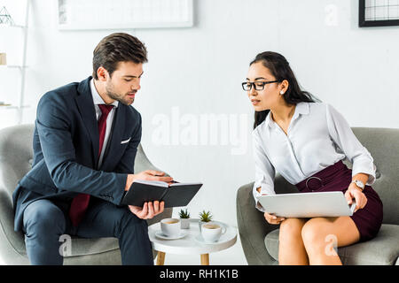 Multiethnischen Geschäftsleute mit Notebook und Laptop Sprechen während der Sitzung in Wartehalle Stockfoto