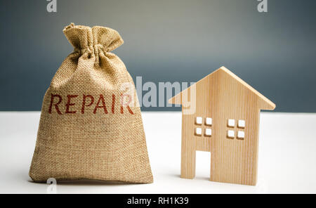 Geld beutel mit dem Wort Reparatur und ein Holzhaus. Speichern und Akkumulation von Geld zu reparieren. Konzept einer neuen Haus, Wohnung oder Gehäuse. konstruieren Stockfoto