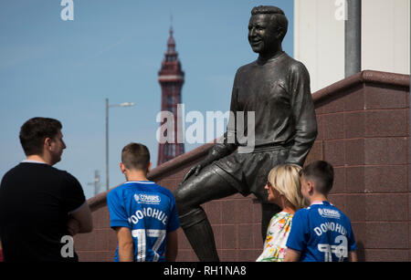 Fans vorbei an der Statue zu ehemaliger Spieler Jimmy Armfield außerhalb Bloomfield Road Stadium vor Blackpool hosted Portsmouth in einem englischen Liga eine Vorrichtung. Das Match verlief durch einen Protest von rund 500 Fans gegen umstrittenes Besitzer des Clubs Owen Oyston, von denen viele nicht das Spiel besuchen. Das Match wurde von den Besuchern durch 2-1 mit zwei Ziele von Ronan Curtis von nur 4,154 fast die Hälfte davon Portsmouth Unterstützer beobachtete, gewann. Stockfoto