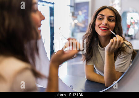 Reflexion der junge schöne Frau mit der Hand in der Nähe der Lippen auf Spiegel im Friseursalon Stockfoto