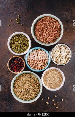 Ansicht von oben auf die Schüsseln mit verschiedenen rohen Körner und Samen auf eine strukturierte dunklen Hintergrund. Stockfoto