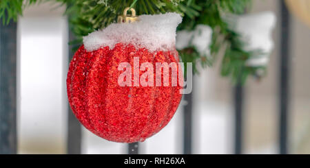 Rote Christbaumkugel hängend an einer Girlande gegen Geländer Stockfoto