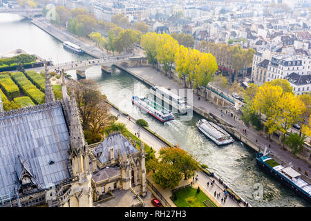 Luftbild vom Turm der Kathedrale Notre-Dame de Paris über den Fluss Seine mit tour Boote kreuzen und Menschen auf den Kaianlagen bummeln. Stockfoto