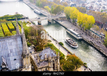 Luftbild vom Turm der Kathedrale Notre-Dame de Paris über den Fluss Seine mit tour Boote kreuzen und Menschen auf den Kaianlagen bummeln. Stockfoto