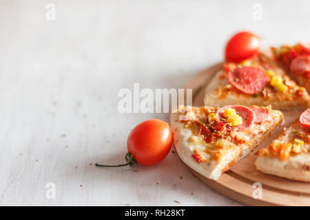 Pizza mit Mais, Würstchen, Tomaten auf Holz- runde Board Stockfoto