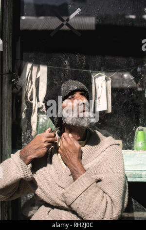 Ein alter Mann trimmt seinen Bart mit der Schere am Straßenrand im Neelum-Tal, Azad Kaschmir, Pakistan Stockfoto