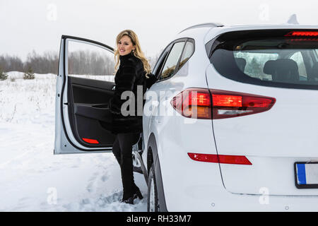 Die blonde Frau aus dem weißen suv Auto und blickt zurück. Stockfoto