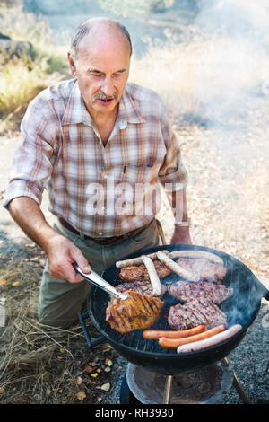 Mann die Zubereitung von Fleisch am Grill Stockfoto