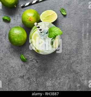 Limonade oder Mojito mit Limette, Minze und Eis auf dunklen konkreten Hintergrund. Kopieren Sie Platz für Text. Ansicht von oben. Im Sommer trinken. Platz crop. Stockfoto