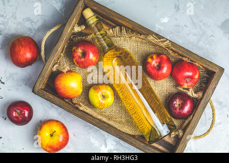 Flasche hausgemachten Organische Apple Cider mit frischen Äpfeln in Feld, Ansicht von oben, Licht gay konkrete Tischfläche. Stockfoto