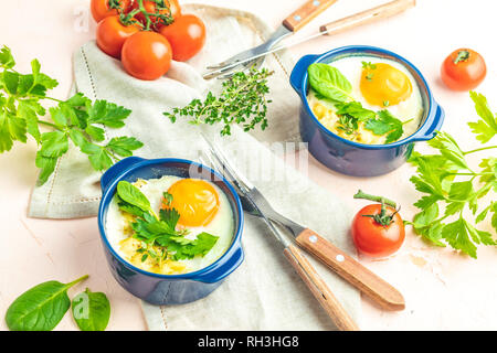 Eier kokot Cocotte französisches Frühstück. Gebackene Eier in blau Keramik Backformen. Portioniert Auflauf aus Gemüse und Eier im italienischen Stil. Stockfoto