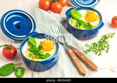Eier kokot Cocotte französisches Frühstück. Gebackene Eier in blau Keramik Backformen. Portioniert Auflauf aus Gemüse und Eier im italienischen Stil. Stockfoto