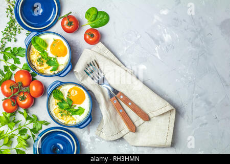Gebackene Eier in blau Keramik Backformen. Portioniert Auflauf aus Gemüse und Eier in der italienischen oder französischen Stil. Eier kokot cocotte Frühstück. Top Stockfoto