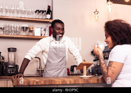 Freundlich lächelnd Barista zu einem Client begeistert Stockfoto