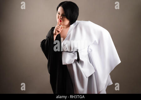 Fat brunette Frau in trendy Kleid auf grauem Hintergrund Stockfoto