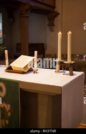 Altar in einer alten Kirche mit einer Bibel und Kerzenschein auf es Stockfoto