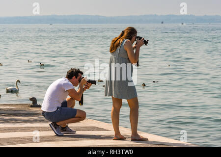 LAZISE, Gardasee, Italien - September 2018: Zwei Menschen Fotografieren auf der Promenade in Lazise am Gardasee. Stockfoto