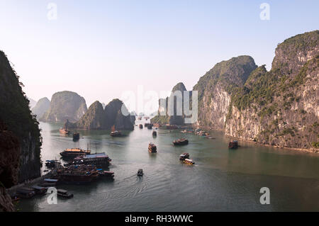 Blick von der Ausfahrt von Sung Sot Höhle Anzeigen über die Bucht von Bo Hon Insel gefüllt mit Holz- Kreuzfahrtschiffe und Kalkstein Karst, Vietnam Stockfoto