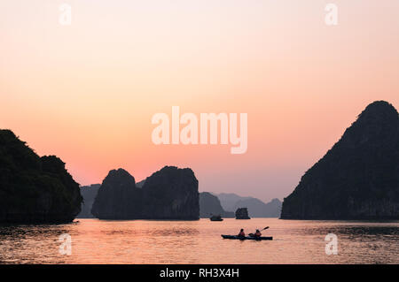 Zwei Touristen in einem Kajak Kajak zwischen den Kalkstein Karst Inseln von Halong oder Ha Long Bucht bei Sonnenuntergang, Vietnam Stockfoto