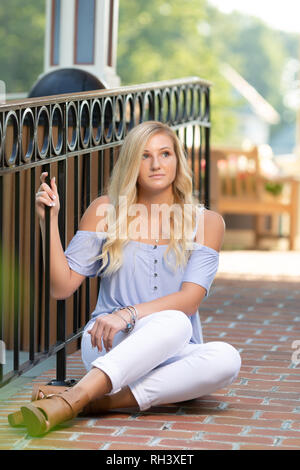 Eine attraktive blonde Haare kaukasischen High School senior posieren für ältere Bilder. Weibliche Teenager Portrait draußen im Park im Sommer. Stockfoto