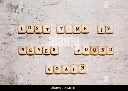 Würfel mit den Worten VERLORENE ZEIT IST NIE WIEDER GEFUNDEN auf einem grauen konkreten Hintergrund. Ansicht von oben selektiven Fokus Stockfoto
