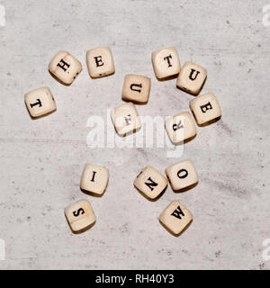 Würfel mit den Worten DER ZUKUNFT IST JETZT auf einem grauen konkreten Hintergrund. Ansicht von oben selektiven Fokus Stockfoto