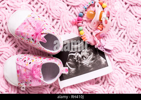 Pink booties neben Bildern des Babys mit Ultraschall bei 20 Wochen der Schwangerschaft. Das Konzept der erwartet ein Baby, Schwangerschaft. Tochter. Selecti Stockfoto