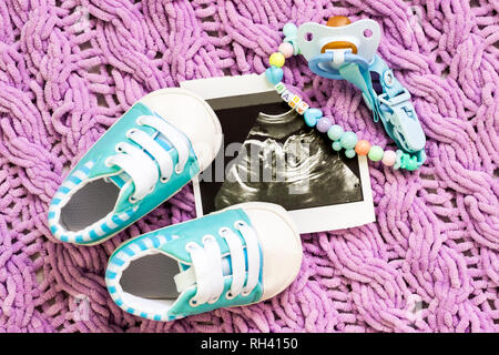 Blau booties Neben Baby Fotos mit Ultraschall bei 20 Wochen der Schwangerschaft. Das Konzept der warten baby boy, Schwangerschaft. Einen Sohn. Selektiver Fokus Stockfoto