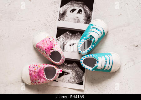 Blau und pink Booties neben Baby Fotos mit Ultraschall in der 4. Woche der Schwangerschaft. Warten auf Zwillinge. Sohn und Tochter. Selektiver Fokus Stockfoto