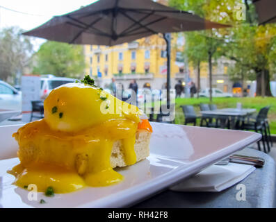 Sonnigen Frühstück mit Brot, Toast, Lachs und pochiertem Ei mit grünen an einem regnerischen Tag in Italien Stockfoto