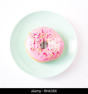 Auf der Suche nach unten von oben auf einen farbenfrohen Pastelltönen Platte mit einem süßen Donut in rosa Zuckerglasur überzogen mit Hunderten und Tausenden auf weißem Hintergrund in ein Stockfoto