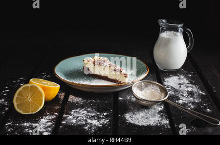 Foto von Schokolade bio Käsekuchen mit Zitronensaft, Milch, weißer Zucker auf Holz- Hintergrund. Dunkle essen Fotografie von süßen und beleuchtete Dessert. Stockfoto