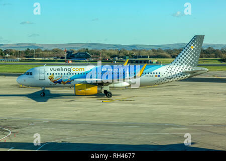 Ein Vueling Airlines Airbus A320-Flugzeuge, registrierte EG-MLE, und zeigt ein livery Werbung 25 Jahre Disneyland Paris, auf dem Flughafen Manchester. Stockfoto