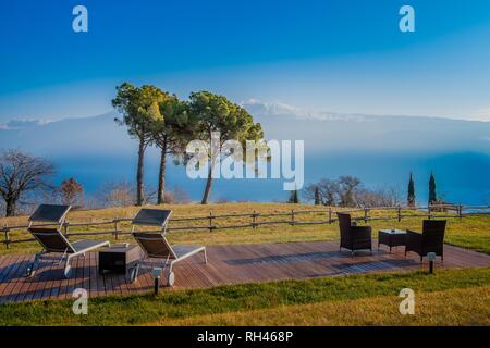 Garten mit Tischen, Stühlen und Liegestühlen mit Blick auf den See eingerichtet Stockfoto