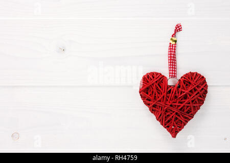 Wicker Herzen hängen auf ein weißes Holzbrett. Valentines Tag Karte konzept mit Platz für Text kopieren. Stockfoto