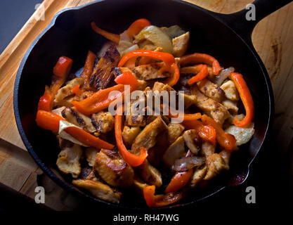 Ohne Knochen, ohne Haut Hähnchen Wokgemüse mit Rot und Orange Paprika und in einer gusseisernen Pfanne serviert. Stockfoto